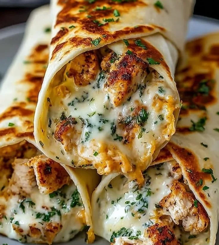 Cheesy garlic chicken wraps served on a plate with fresh ingredients