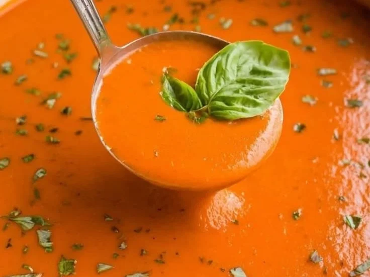 Delicious creamy tomato bisque soup in a bowl garnished with fresh herbs.