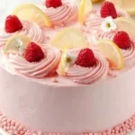 Lemon raspberry layer cake decorated with fresh raspberries and lemon zest.