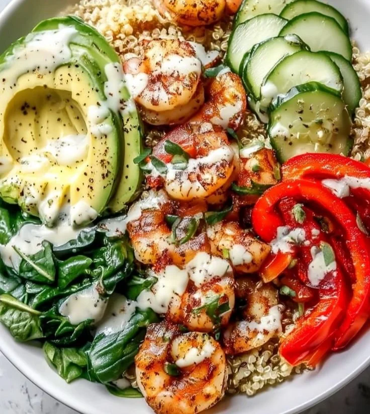 Delicious shrimp quinoa bowl garnished with fresh vegetables and herbs.