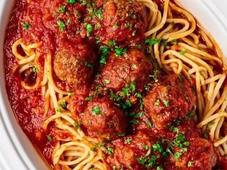 A bowl of slow cooker spaghetti and meatballs topped with fresh parsley