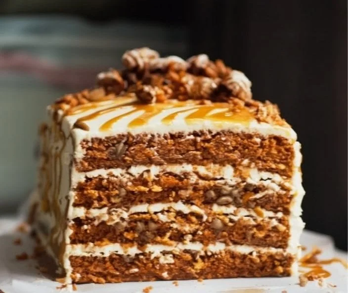 Ultimate carrot cake topped with candied pecans on a decorative plate.