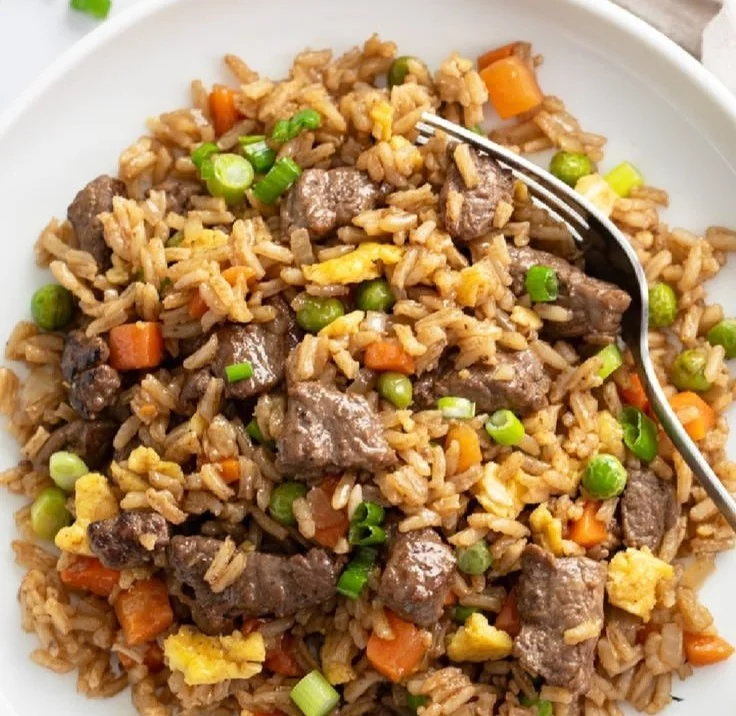 Plate of beef fried rice with colorful vegetables and tender beef pieces