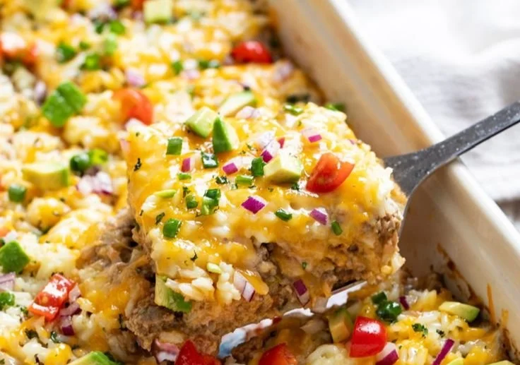 Delicious and colorful burrito casserole topped with melted cheese and fresh toppings.