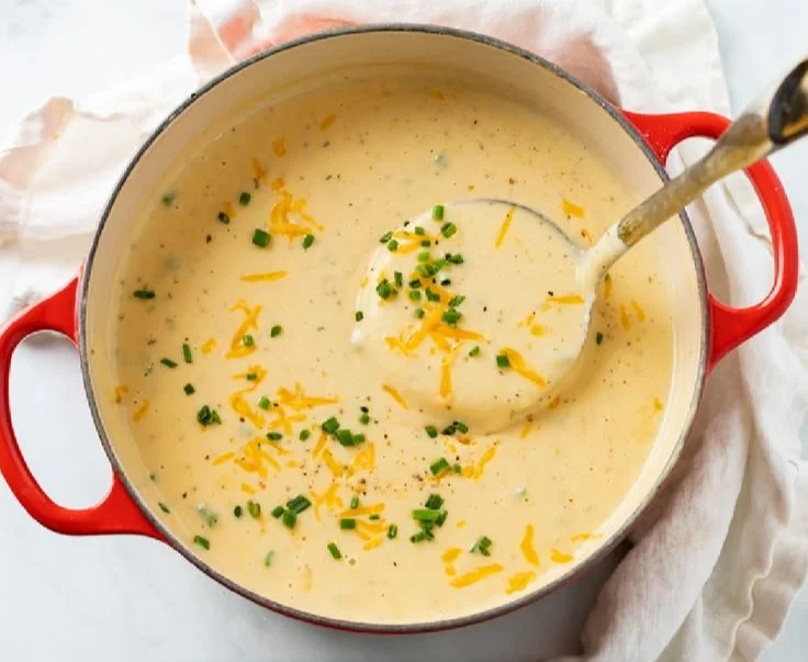 Bowl of Cheesy Potato Soup garnished with herbs and cheese