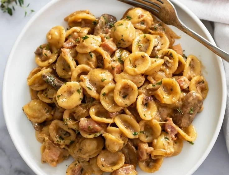 A delicious bowl of French Onion Pasta topped with melted cheese and caramelized onions.