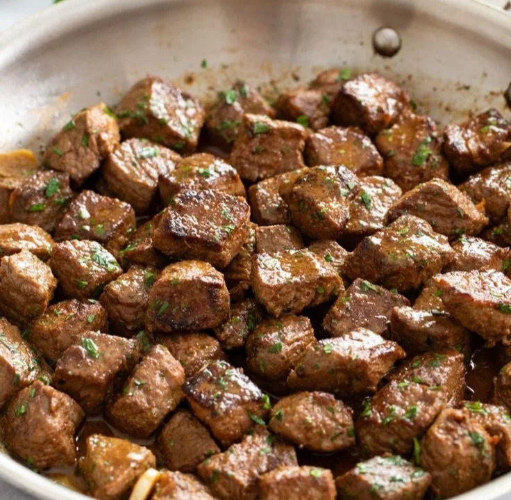 Garlic butter steak bites served on a plate with herbs