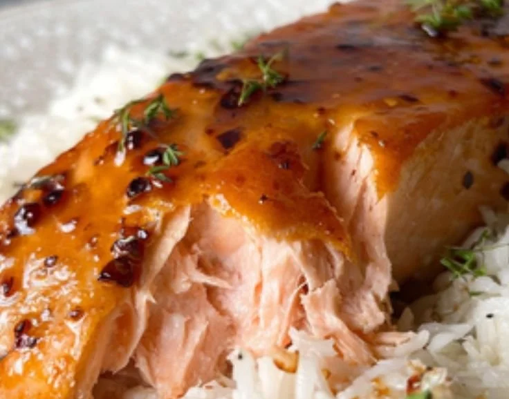 Delicious honey glazed salmon fillet garnished with herbs and served on a plate