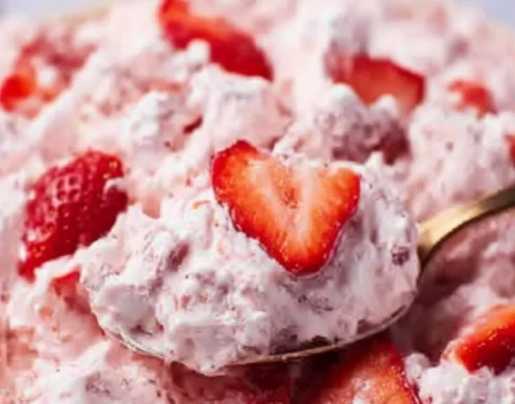 Bowl of colorful Strawberry Fluff Salad with fresh strawberries and cream.