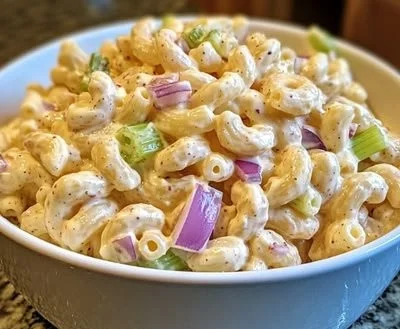 Plate of Guy Fieri's flavorful macaroni salad topped with fresh herbs and vegetables.