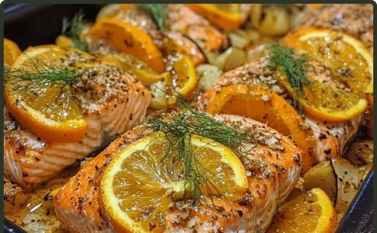 Mediterranean baked salmon garnished with fennel and orange slices on a plate.