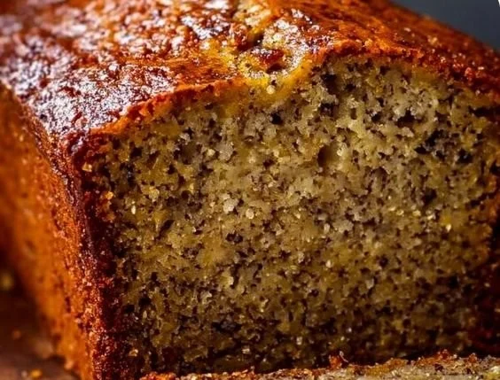 Slice of perfect moist banana bread on a wooden cutting board.