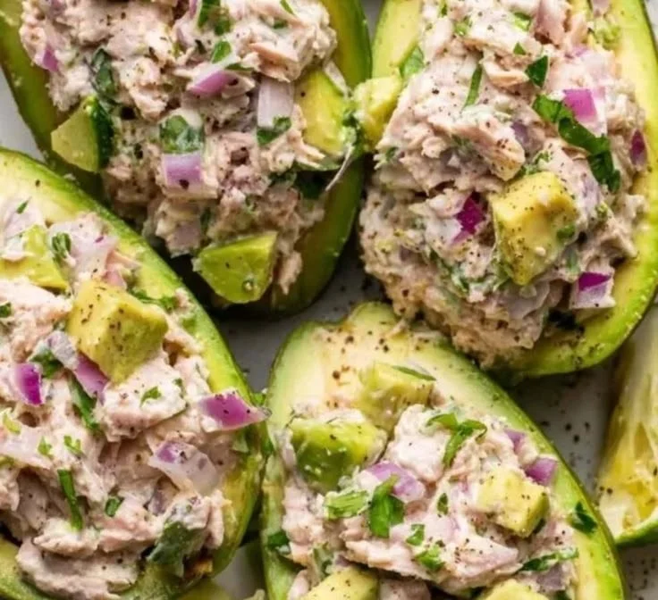 Avocado tuna salad boats served on a plate with fresh ingredients