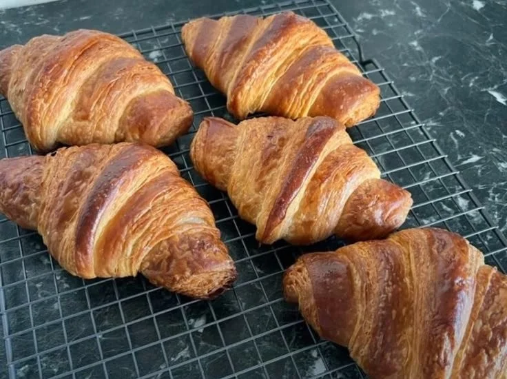 Freshly baked classic French croissants on a wooden table.