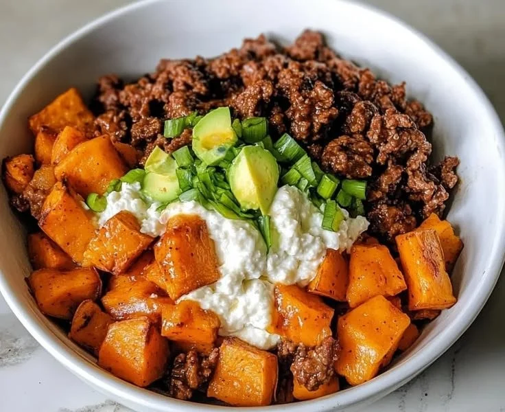 High-protein beef sweet potato bowls topped with fresh herbs and spices.
