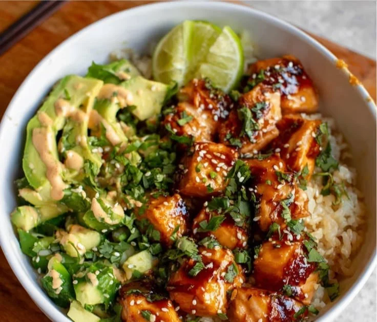 Honey glazed salmon served in a rice bowl with fresh vegetables and garnishes