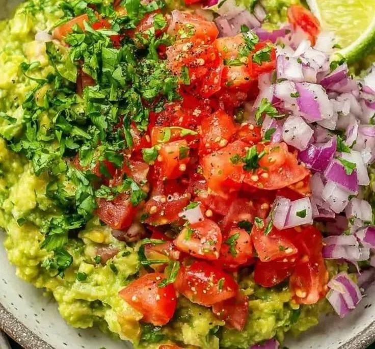 Bowl of authentic guacamole with fresh ingredients next to tortilla chips.