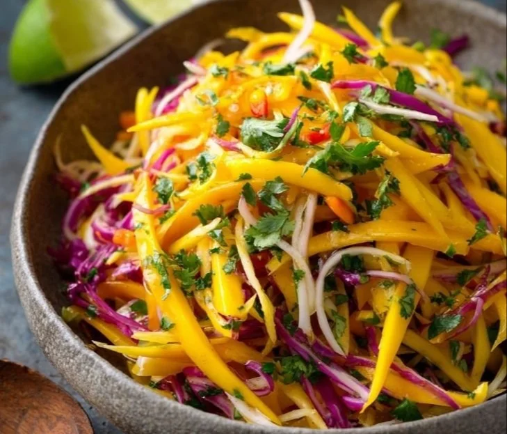 A bowl of colorful Mango Slaw with fresh mango, cabbage, and herbs.