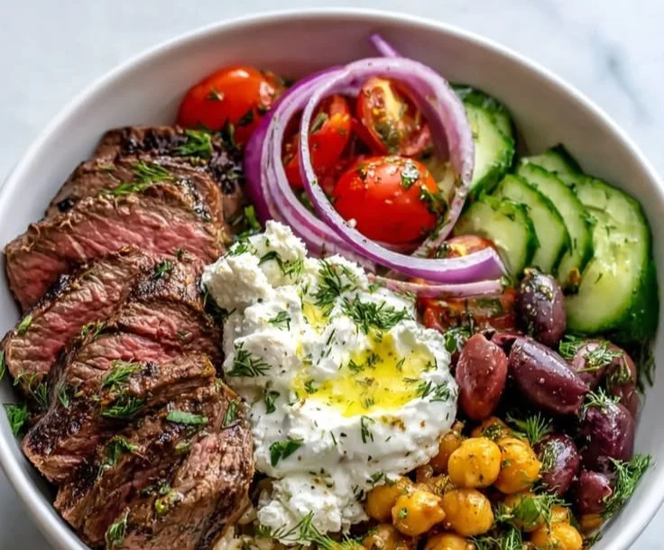 Mediterranean steak bowl with fresh vegetables and herbs