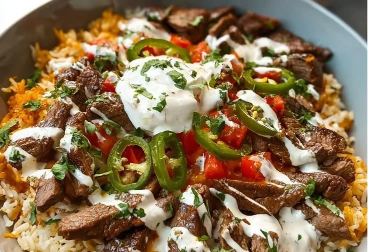 Delicious steak queso rice bowl topped with fresh ingredients and cheese