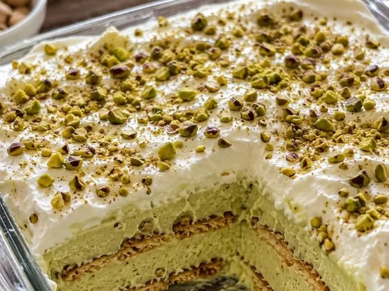 Homemade creamy pistachio pudding in a dessert bowl with a sprinkle of nuts on top.