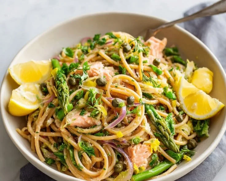 Delicious lemon salmon pasta dish garnished with herbs and lemon slices.