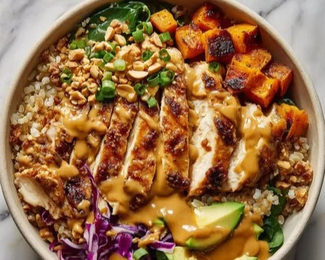 Peanut chicken bowl with colorful vegetables and rice in a meal prep container